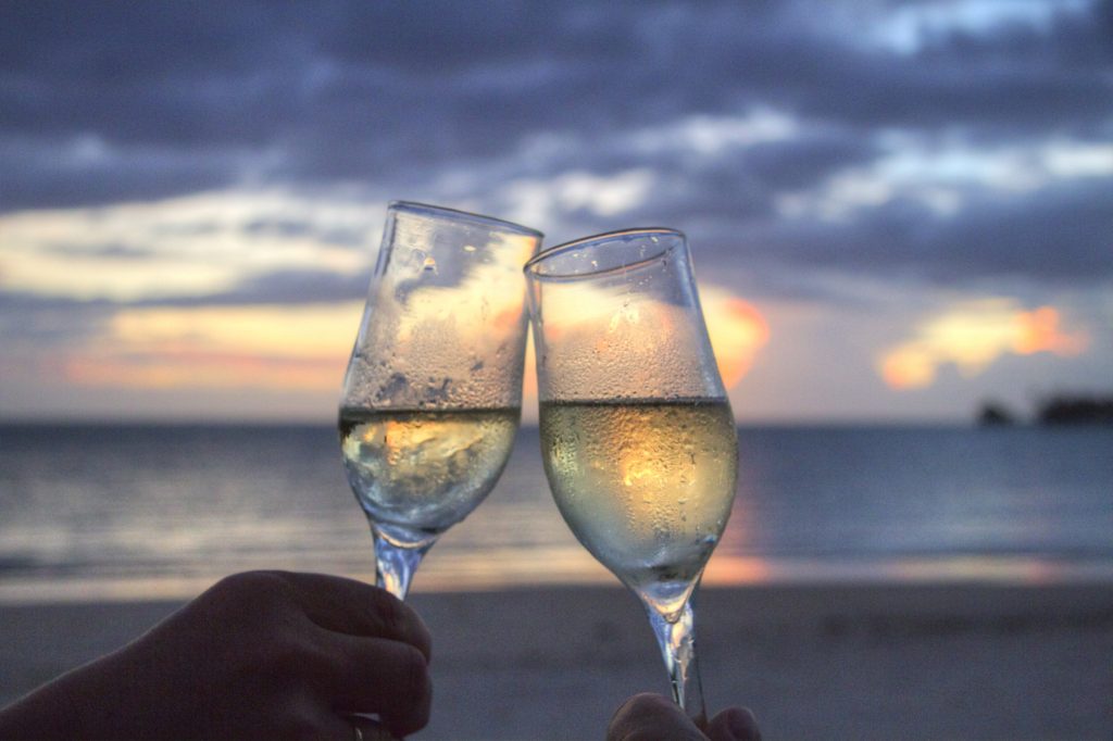 a picture of two glasses of white wine against a sunset backdrop.
