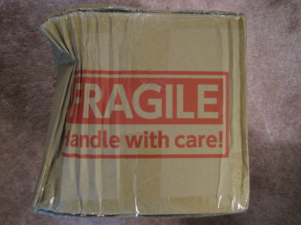 A picture of a heavily damaged package labeled fragile - handle with care to signify proper order fulfillment needs to consider damage in transit.