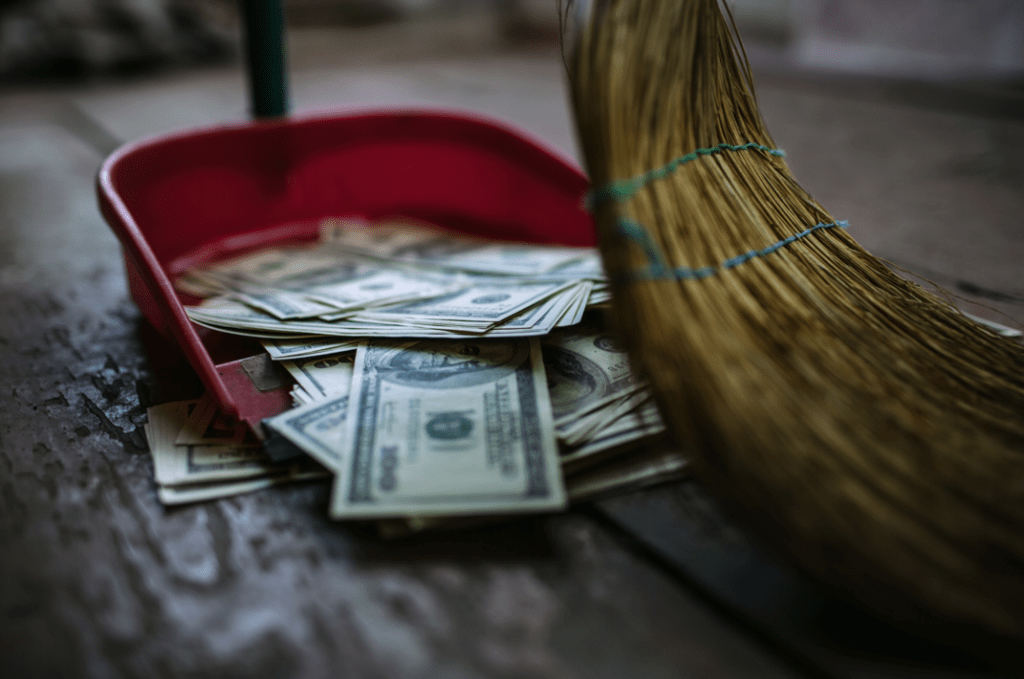 a picture of a broom sweeping money into a dustpan.