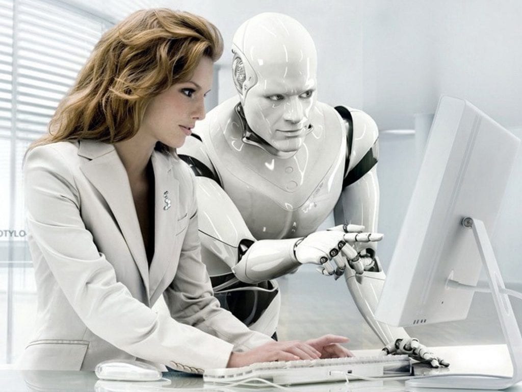 a photo of a Chief Robotics Officer and a robot discussing information on a computer monitor