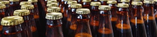 a photo of glass beer bottles on a bottling line in a food and beverage manufacturing brewery - encompass solutions.