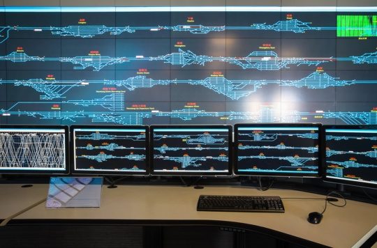 An image of a railway control room with monitors displaying a full rail system as part of IIoT connectivity.